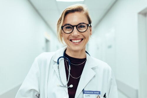 A doctor smiles while looking directly at the camera.