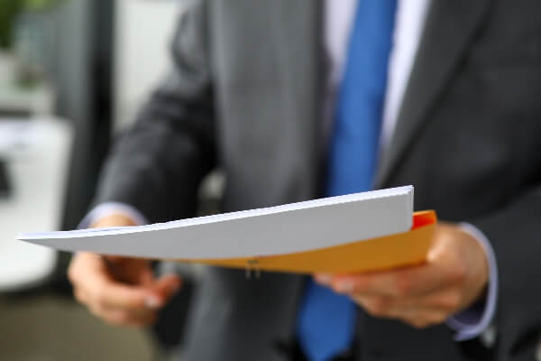 A man in a suit hands off legal documents to serve a process.