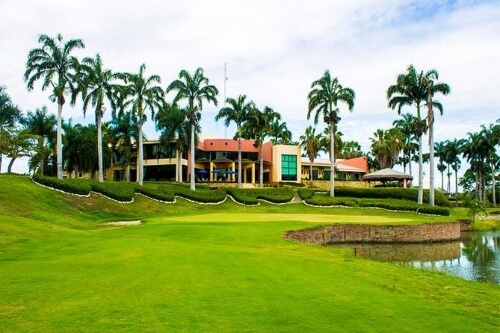 A country club golf course is shown with palm trees and a manicured lawn. 