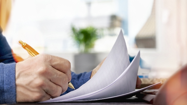 A business person signs a document with a golden pen, authenticating the document.