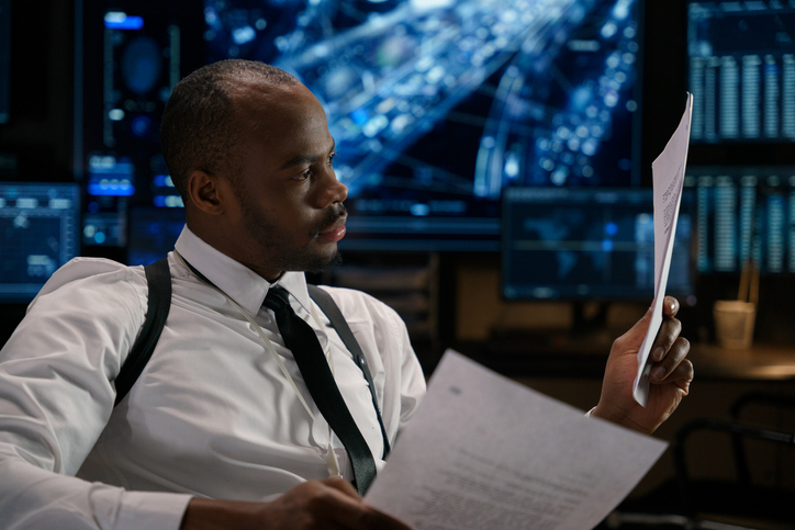 A private investigator pours over two documents in an effort to track down a target.