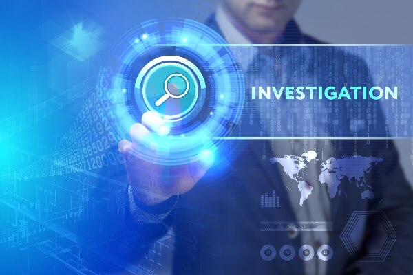 A man in a suit clicks on a digital image with the word investigation floating in the middle.